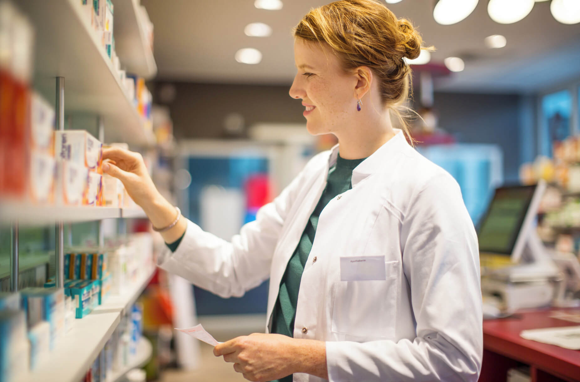 Pharmacist reaching for prescription and smiling