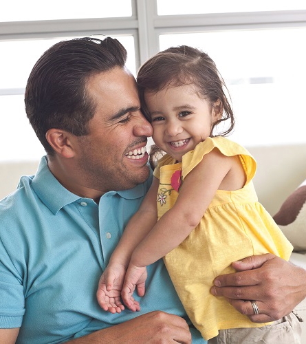 Padre abrazando a su hija sonriente.