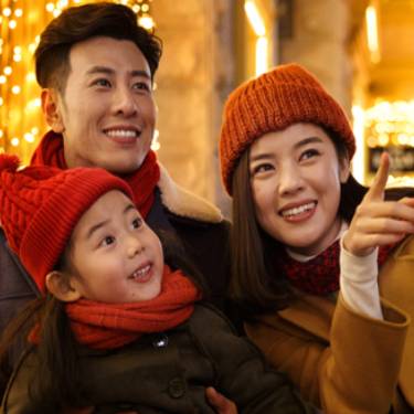 Happy family smiling under holiday lights.