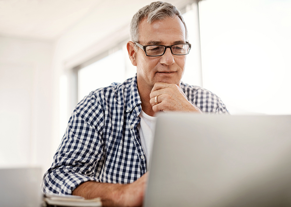A middle-aged man viewing a laptop.