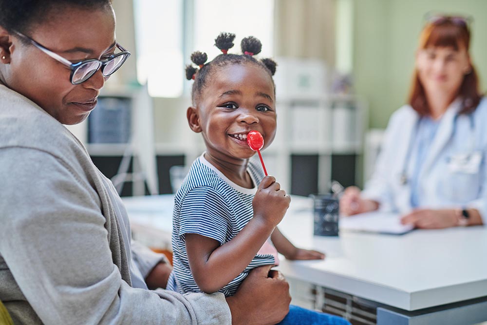 Young girl sitting in moms lap at doctor