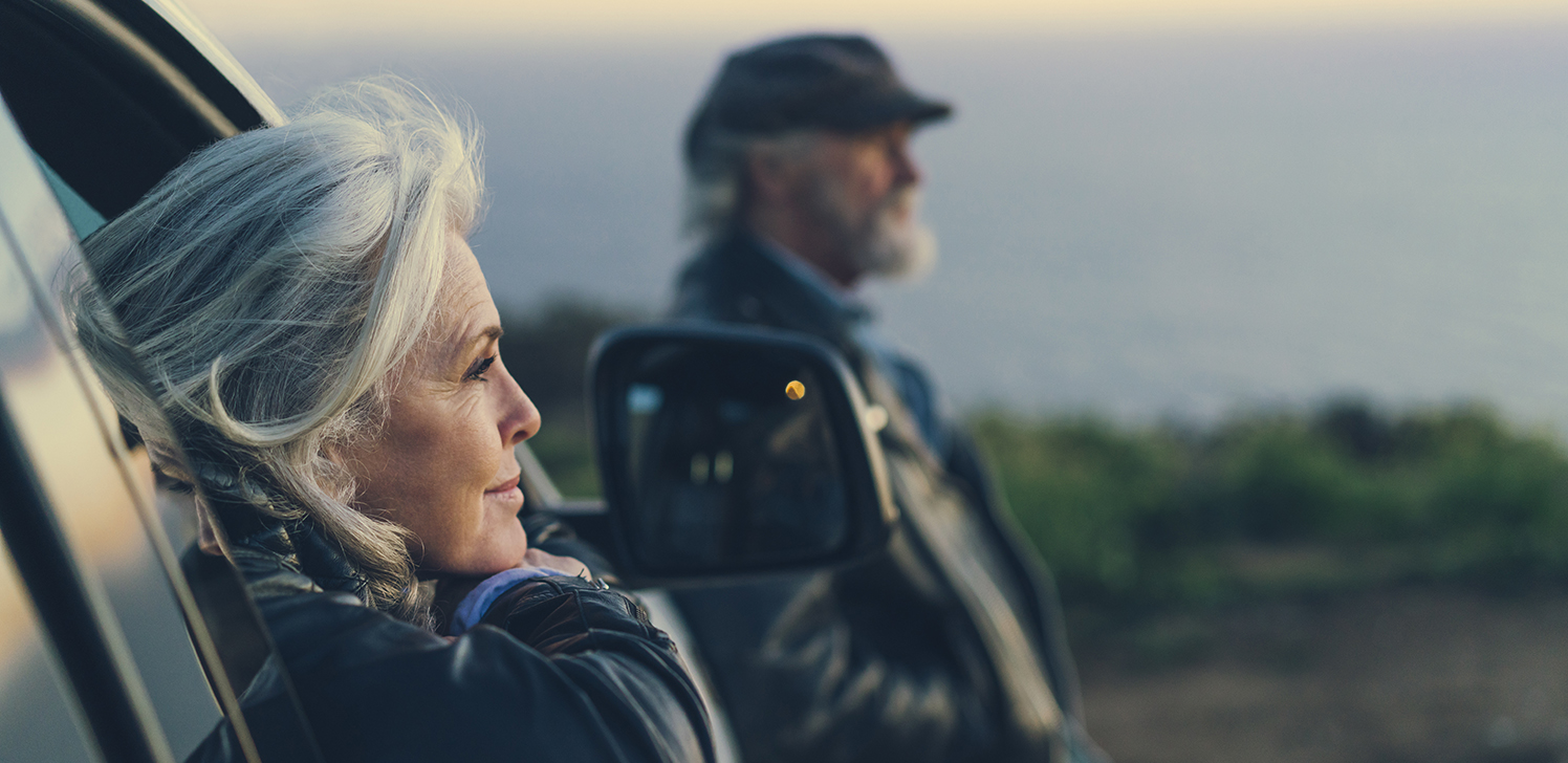 Retirees enjoy a scenic view from their car.