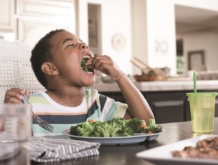 Boy eating healthy broccoli