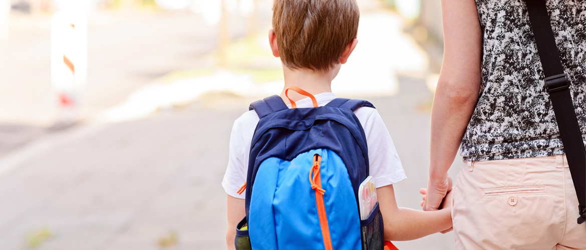 Young children pose for camera outside on playground amidst blue skies and snow