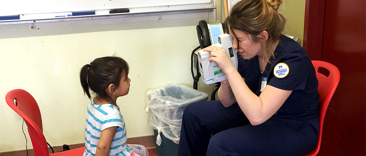Nursing student performs screening on a little girl sitting across from her