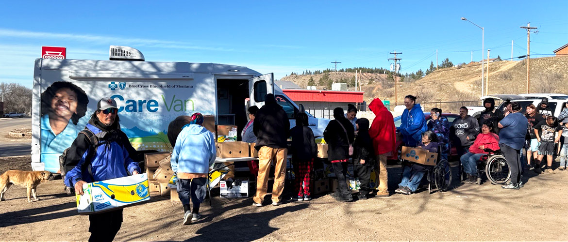 People wait in line for boxes of food handed out by BCBSNM Care Van employees in desert