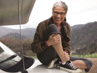 Fearless mature woman seated on her RV with mountains in the background