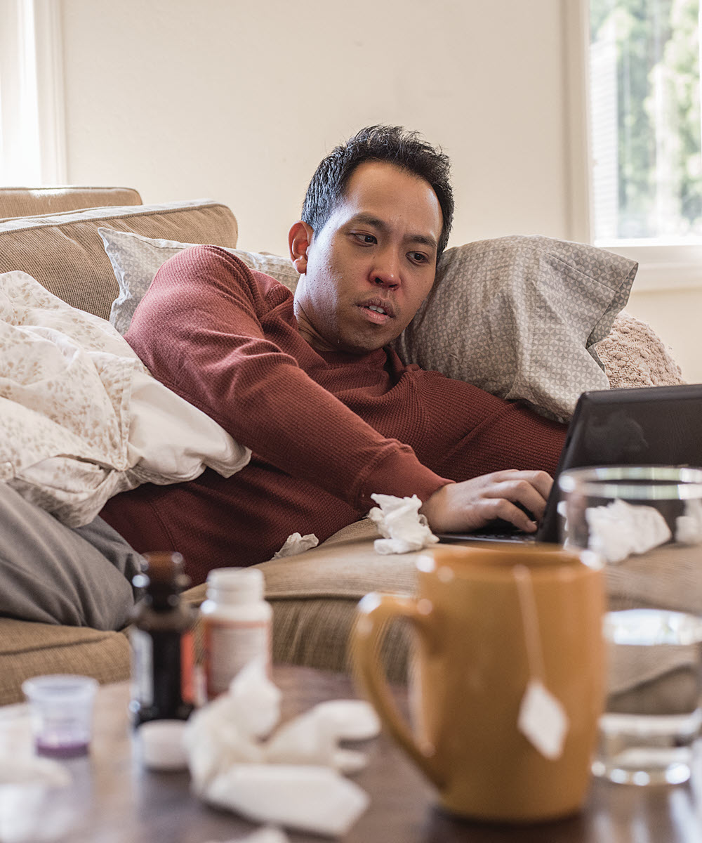Man on couch having telemedicine visit from laptop