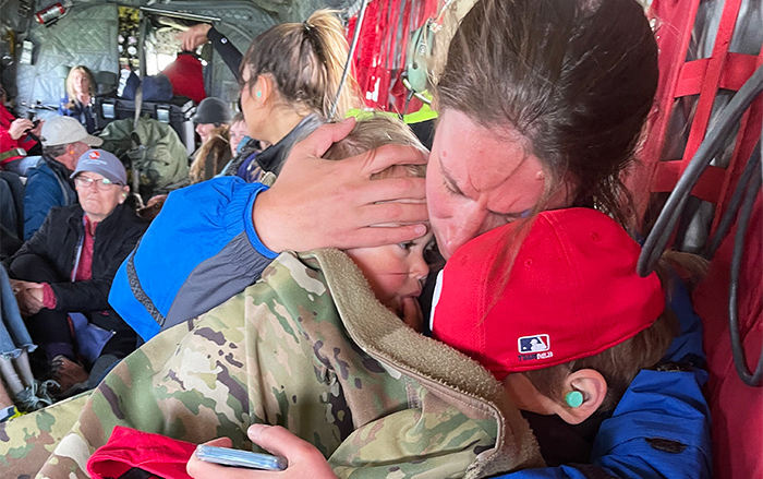 Woman and two small children embrace in a helicopter after historic floods.