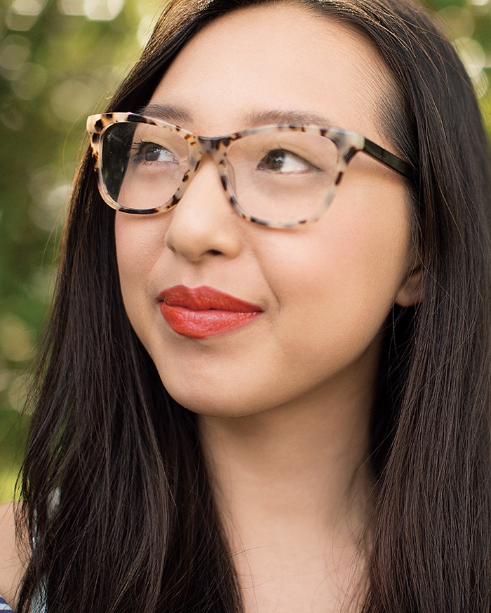 Woman wearing glasses gazes into distance.