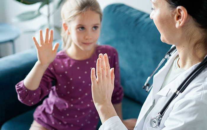 Physician and young patient holding up hands
