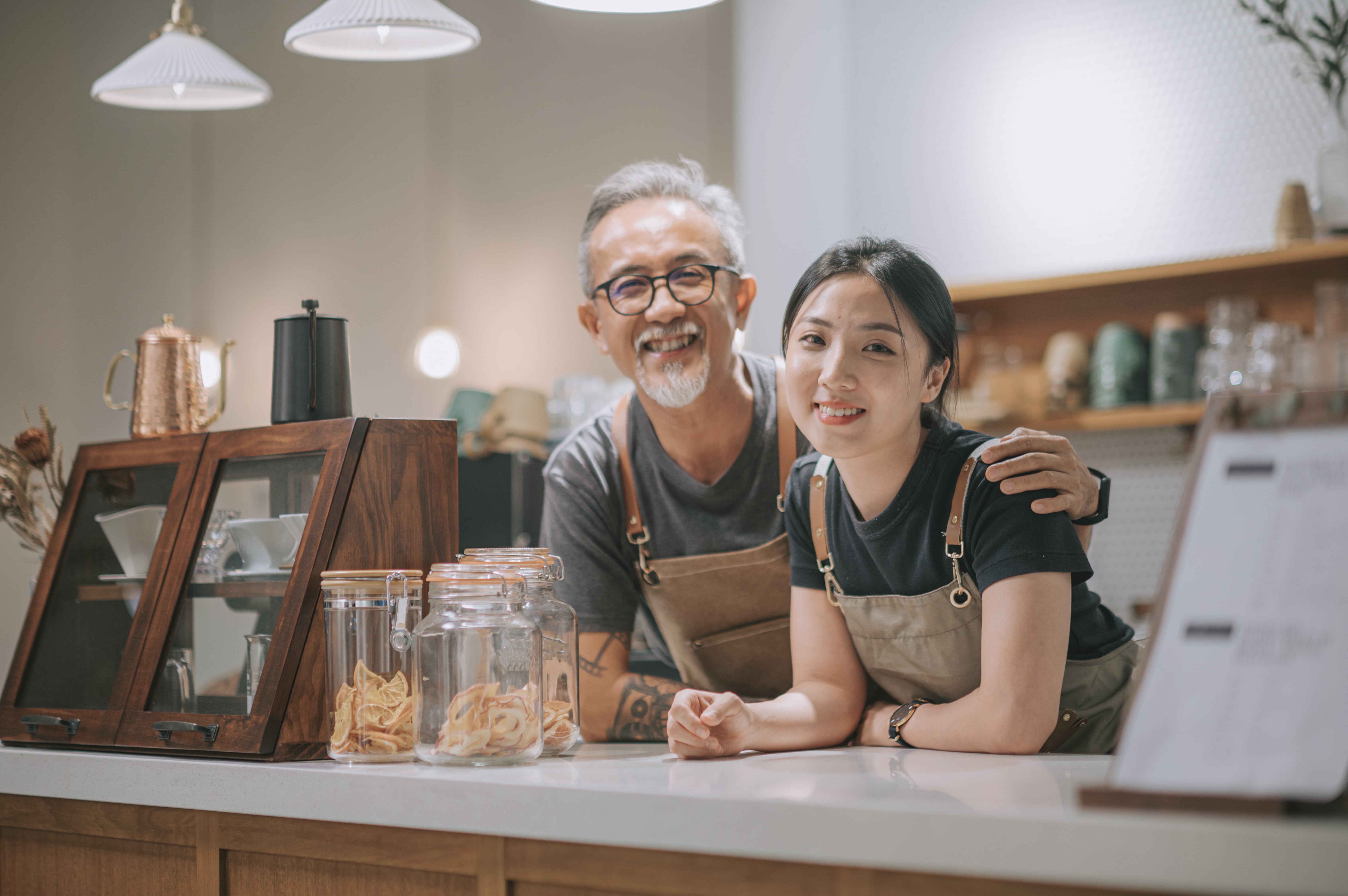 Empleado y empleada de una cafetería de pie detrás del mostrador